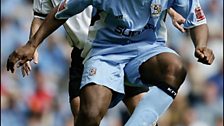 Dele Adebola fends off the challenge from Derby's Jeff Kenna.