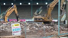 The West Stand is obscured by machinery.