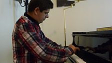 Pianist Javier Perianes warming up under a photo of the great Spanish pianist Alicia de Larrocha