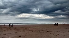 Re-enacting the mounted lookouts of the first life boat service under moody skies on Bamburgh beach