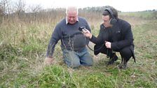 Chris shows Paul one of the plants in the field