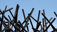 A seemingly chaotic dome of black rods is positioned over a grass plinth – a reference to Chaos Theory.