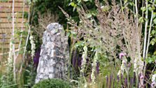 Flint sculptures at the end of the water act as focal points framed by multi-stemmed birch trees.