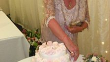 Putting the finishing touches on a wedding cake whilst all dressed up for the ceremony