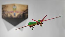 The exhibition includes brightly painted models of drones as well as paintings