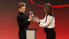 Judge Deborah Bull presents Rhys Antoni Yeomans with the Ballet trophy