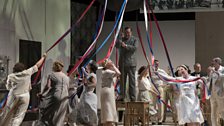 Peter Auty as Dr. Suda with members of the Chorus of Opera North