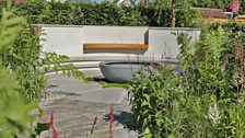 Curves from grasses, paving and hedges flow towards a central seating area and water feature