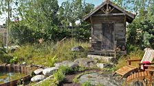 The woodland path leads through the garden to a stone-paved seating area, the sauna has a sedum roof