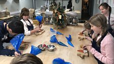 Children busy at work icing their cookies