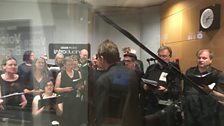 Commoners Choir performing live through the glass of one studio to the other at ˿ Leeds.