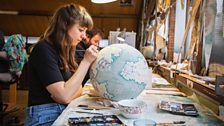 A painter adds land shading to the continents