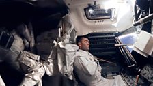 An exhausted and cold Fred Haise is grabs some sleep (centre) as Jack Swigert is curled up in the storage area on the left.