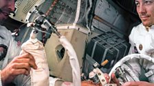 Jack Swigert (right) looks at Jim Lovell as they work together. The CO2 filter is visible behind them.