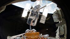 The Space Shuttle Atlantis' robotic arm lifts the Hubble Space Telescope from the cargo bay on May 19, 2009