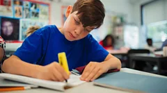Classroom primary English student reading from books and highlighting with yellow pen