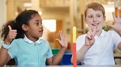 Two children in a primary school maths class holding fingers up to count numbers