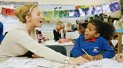 Teacher and girl in a primary school English class learning how to write and read