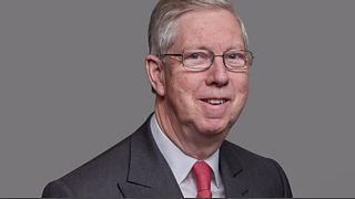 A man with glasses and a grey suit.
