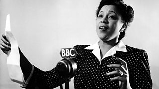 A black woman holding a script with a BBC microphone in the foreground.