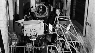 A BBC camera pointing down a complicated series of lenses and mirrors.