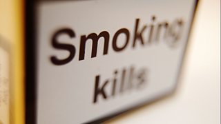 Close-up of an open packet of cigarettes showing 'smoking kills' warning