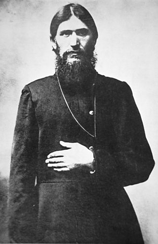 Bearded man with long hair and beard wearing a cassock