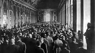 People gather in room to witness the signing of the Treaty of Versailles.