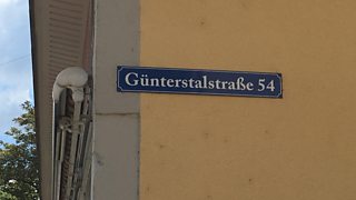 A sign displaying a German address with the number after the street name