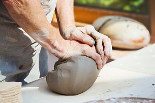 Hands preparing a lump of wet clay