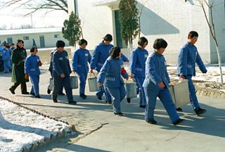Women prisoners carry dining utensils at a prison in Beijing, China