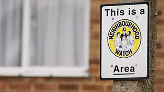 A Neighbourhood Watch sign on a lamp post.