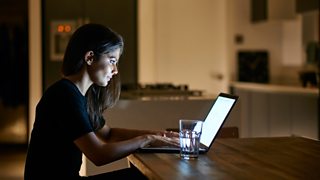 Woman on laptop in kitchen at night