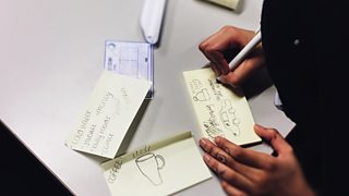A student sketching an idea on a post-it note
