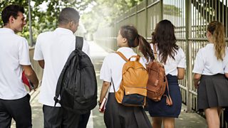 Teenagers in school uniform with backpacks walking in a group