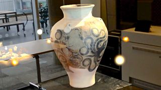 A large ceramic jar placed on a table with glowing yellow spheres floating around it