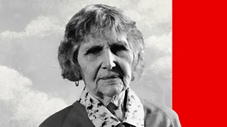 An elderly woman wearing a flowery shirt looks into the camera.