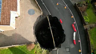 a aerial view of a huge sink hole in the back garden and on part of a street