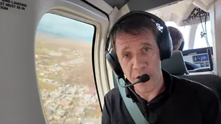 Man in a helicopter wearing a headset.
