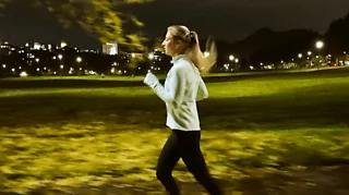 Side view of a woman in casual wear running in a park in the evening