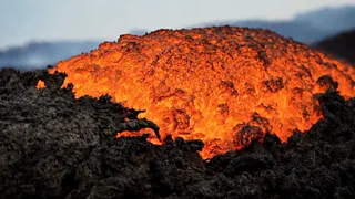 Lava seen bubbling against charcoal rocks