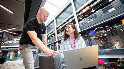 Dau gydweithiwr BBC yn trafod gwaith dros liniadur