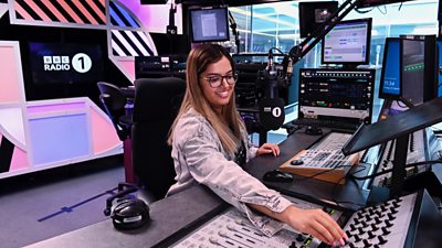 Cydweithiwr BBC yn gweithredu offer sain mewn stiwdio BBC Radio