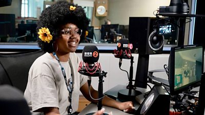 Cydweithiwr BBC wrth feicroffon mewn stiwdio radio