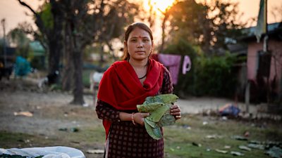 Bhawana Pulami is pictured in her garden, holding a green vegetable while she looks at the camera