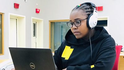 a young woman in headphones looks at a laptop