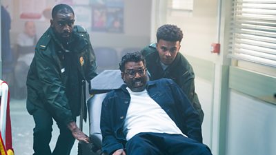 Casualty stars Charles Venn and Milo Clarke roll Romesh through the hospital on a trolley