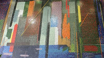 A huge mural on the wall at Television Centre in multiple colours, perhaps resembling skyscrapers.