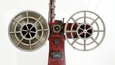 A huge recording contraption with two large circular spools, with the recording head in the centre.
