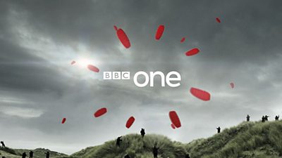 People flying red kites on sand dunes form a spiral encircling the BBC One logo